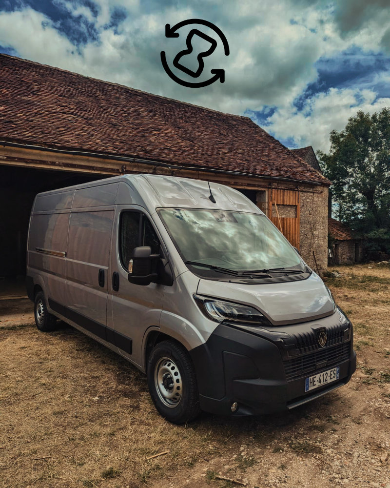 Photo d'un Peugeot Boxer gris devant l'atelier MadVans avec une icône de travail en cours